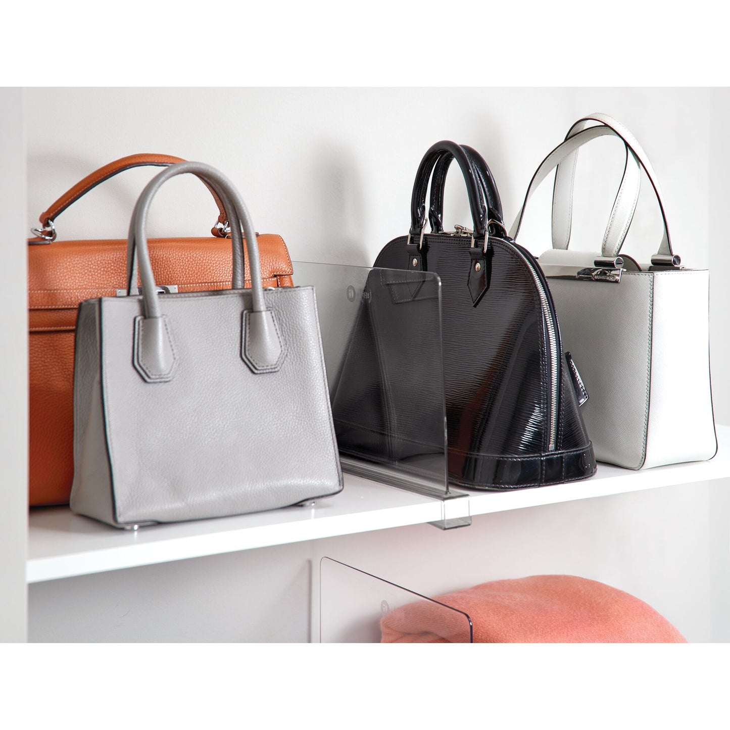 Four handbags displayed on a white shelf with a neutral background