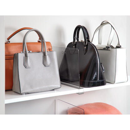 Four handbags displayed on a white shelf with a neutral background