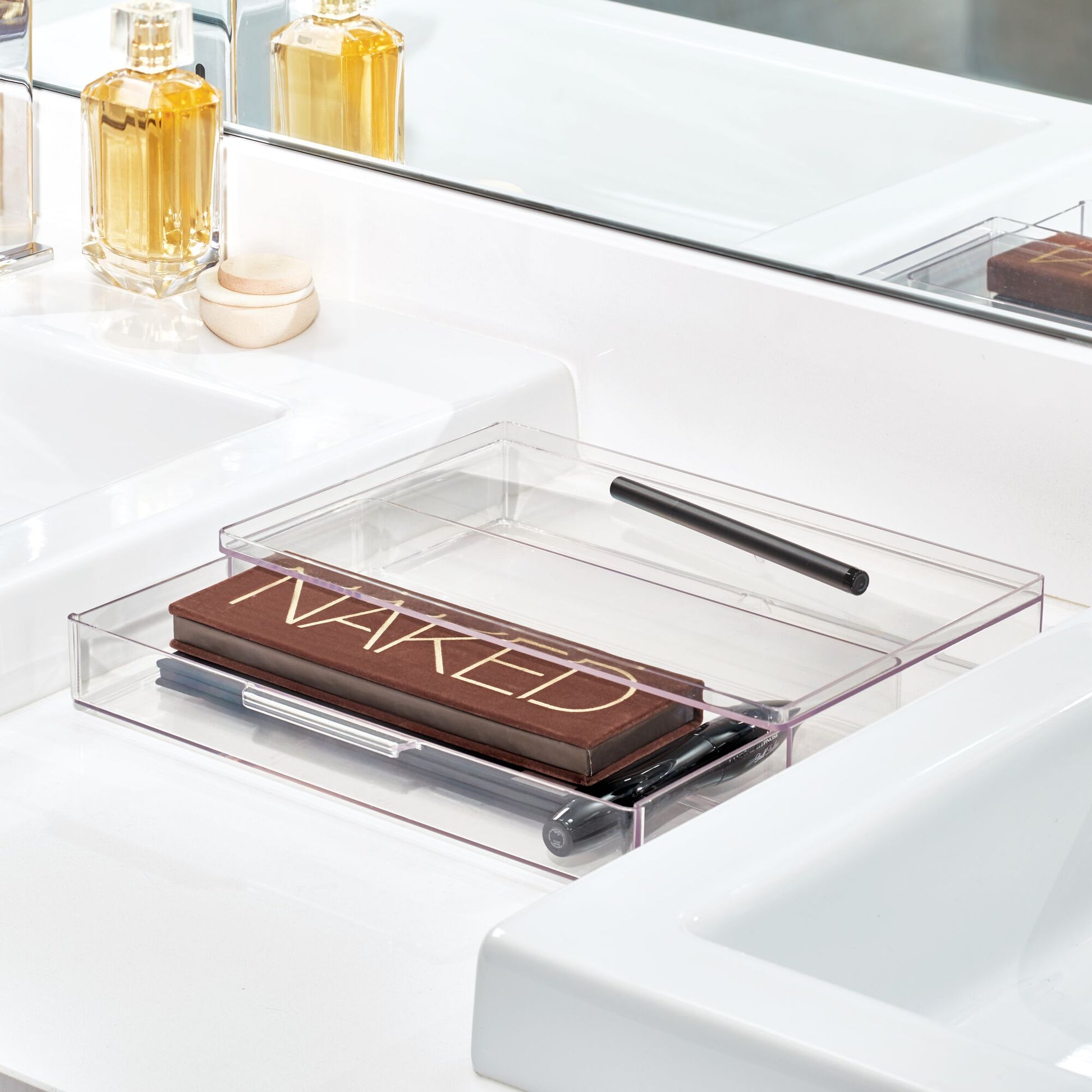 Clear acrylic tray with a makeup palette labeled 'Naked' on a bathroom counter.