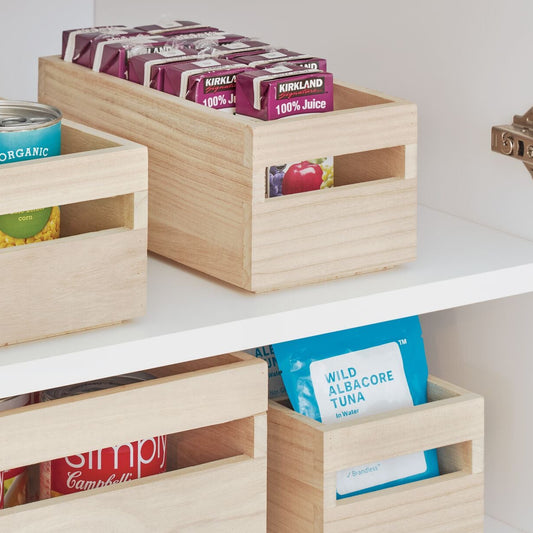 Wooden storage crates with food items on a white shelf