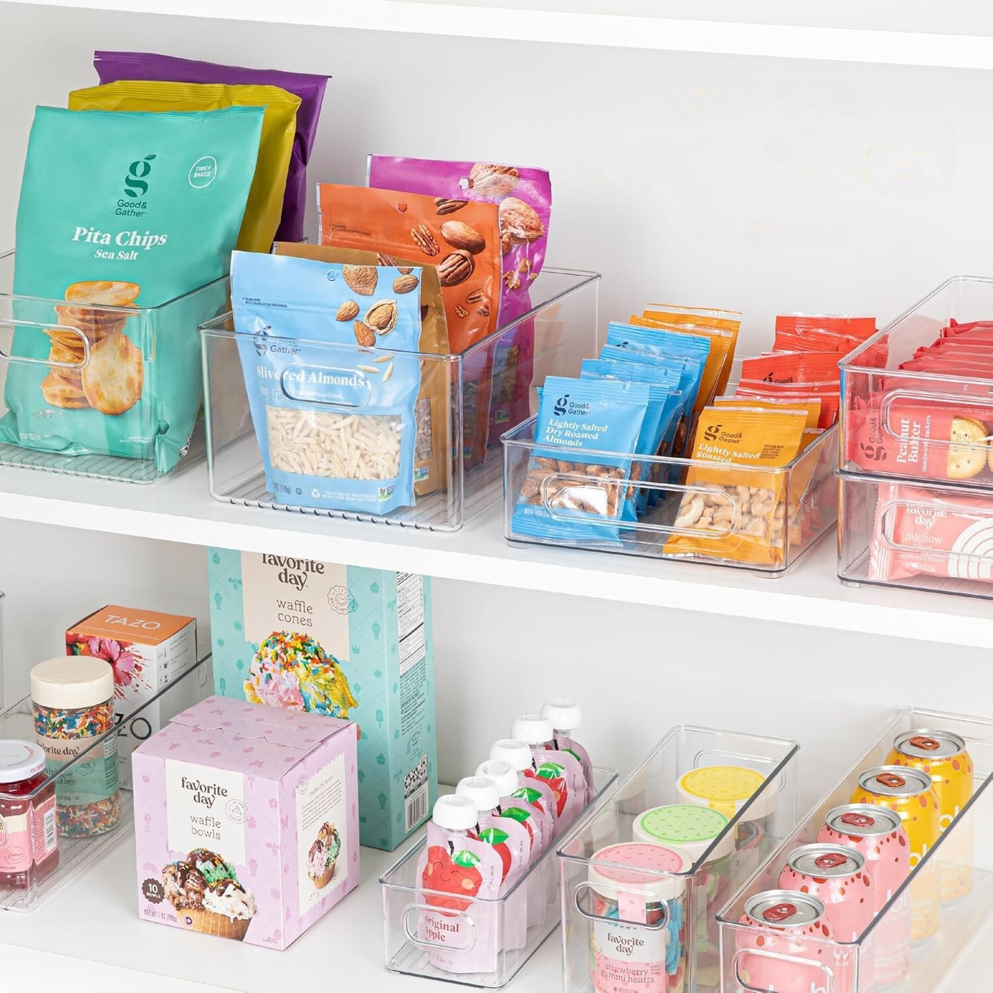 Shelf with various food products including pita chips, snacks, and drinks in clear containers.