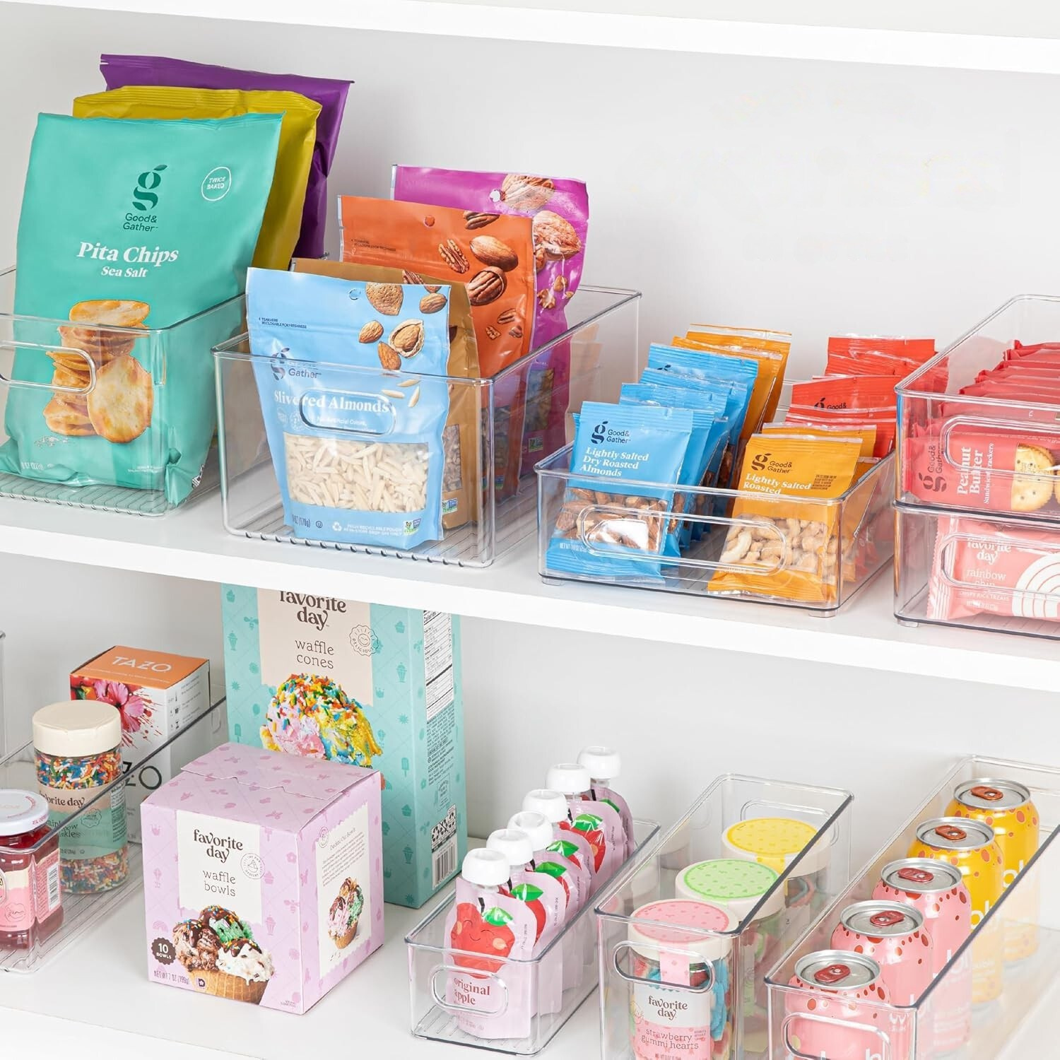 Shelf with various food products including pita chips, snacks, and drinks in clear containers.