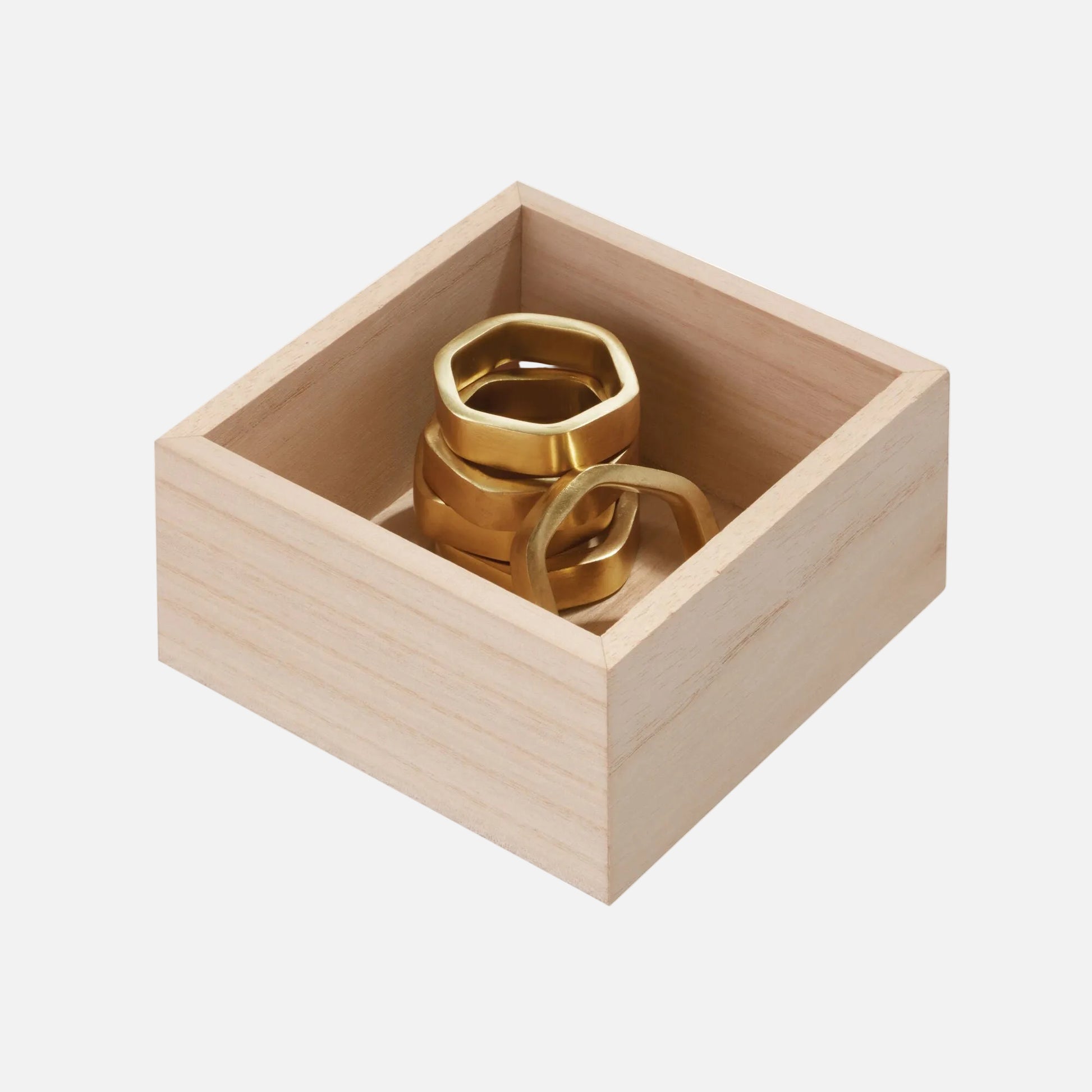 Three polished gold-toned metal rings displayed inside a small square light wood box on a plain white background.