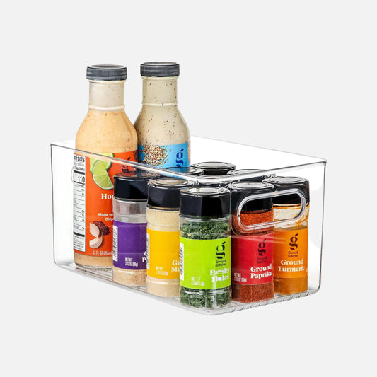 Clear plastic spice rack with various seasoning bottles on a white background